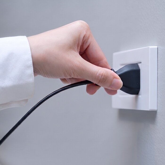 A hand plugging the BlizzAir power cable into a wall outlet
